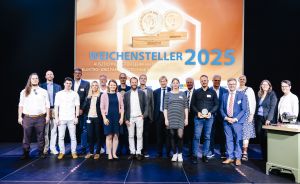 Gruppenfoto von etwa 20 Personen vor einer Leinwand mit der Aufschrift „Weichensteller 2025" bei einer Preisverleihung.