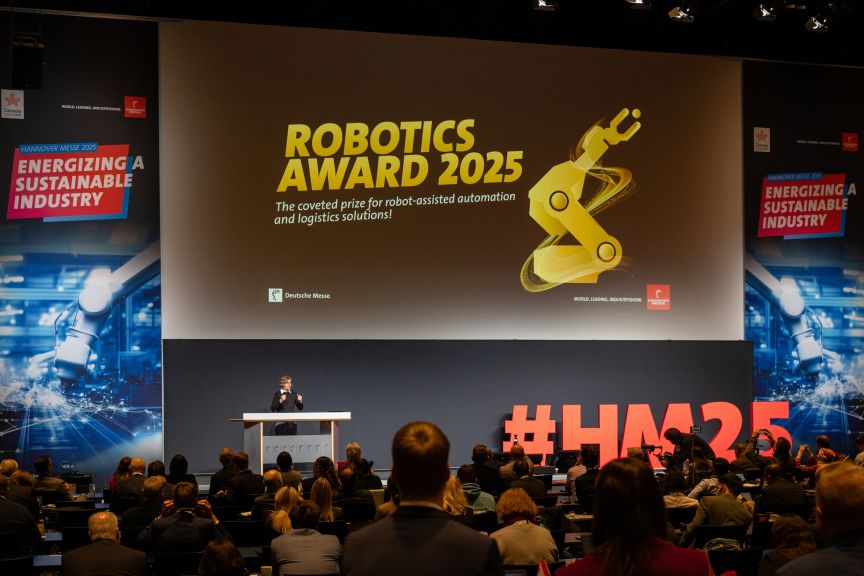 Vortragender auf Bühne vor Leinwand mit „Robotics Award 2025"-Präsentation, Publikum im Vordergrund, Hashtag #HM25 sichtbar.