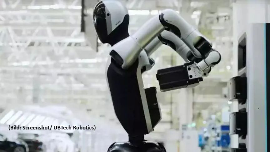 Weißer Humanoid-Roboter von UBTech Robotics greift mit Arm nach einem Gegenstand in einer Industrieanlage.